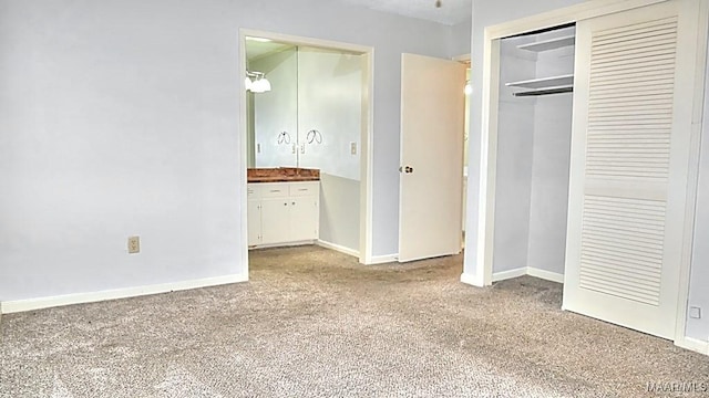 unfurnished bedroom with carpet floors, a closet, connected bathroom, and baseboards