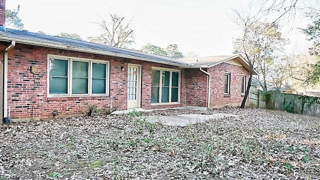 back of property featuring brick siding and fence