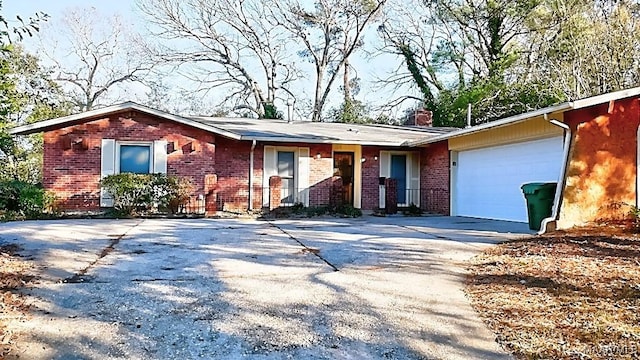 ranch-style house featuring brick siding, driveway, a chimney, and an attached garage