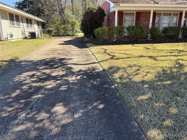 view of home's exterior featuring a lawn, central AC, and brick siding