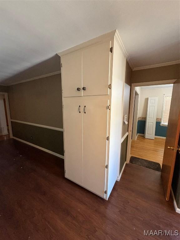 interior space with ornamental molding, dark wood finished floors, and baseboards