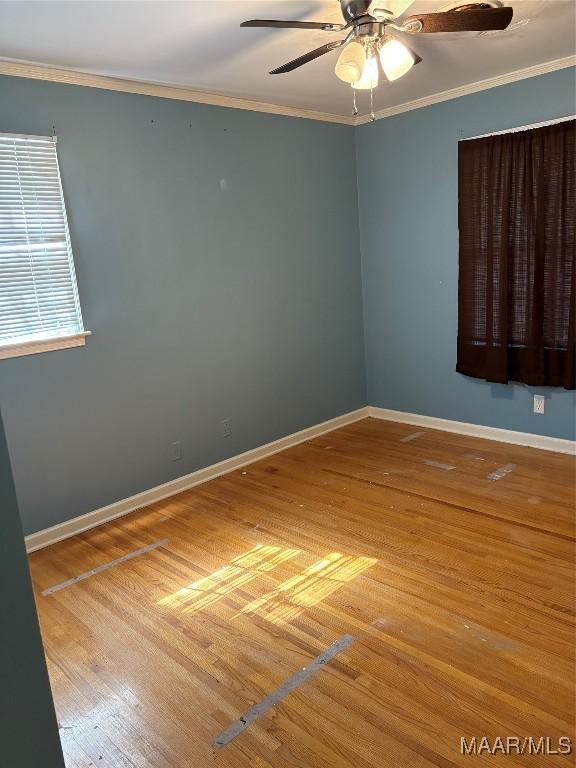 spare room with baseboards, ceiling fan, wood finished floors, and crown molding