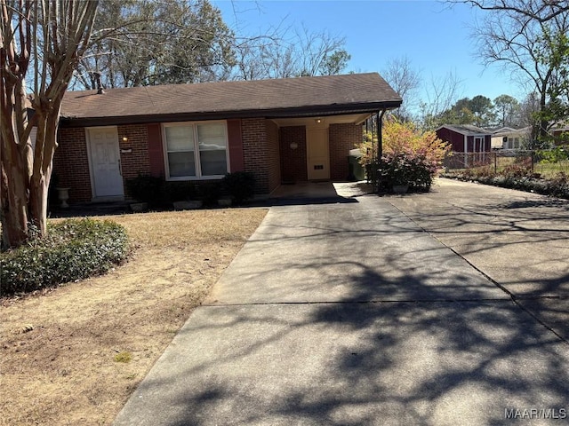 view of front of house with a shingled roof, brick siding, and fence