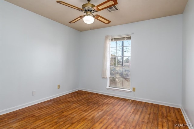 empty room featuring a ceiling fan, baseboards, visible vents, and wood finished floors