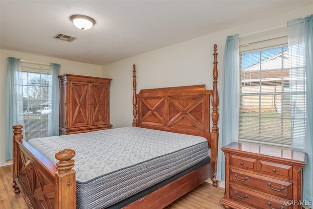 bedroom with light wood-style floors and visible vents