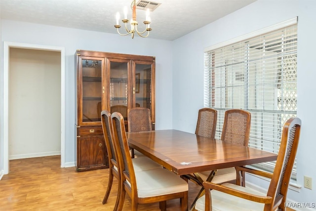 dining space featuring visible vents, a notable chandelier, light wood-style flooring, and baseboards