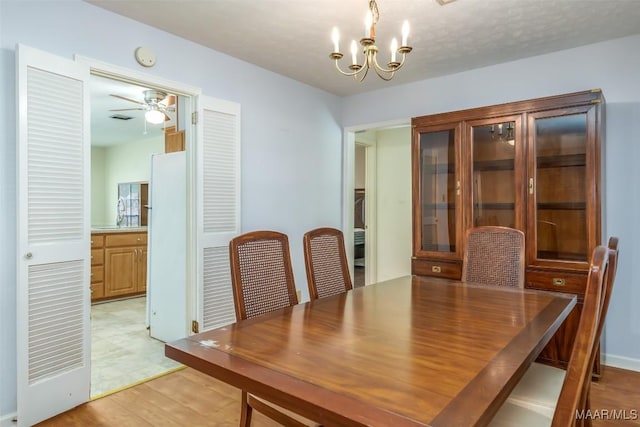 dining space featuring light wood-style floors and ceiling fan with notable chandelier