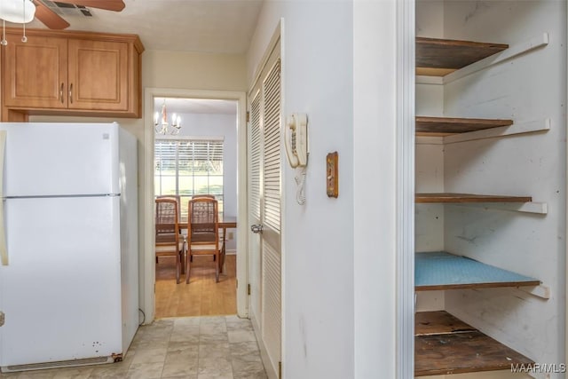 kitchen featuring visible vents, open shelves, ceiling fan with notable chandelier, and freestanding refrigerator