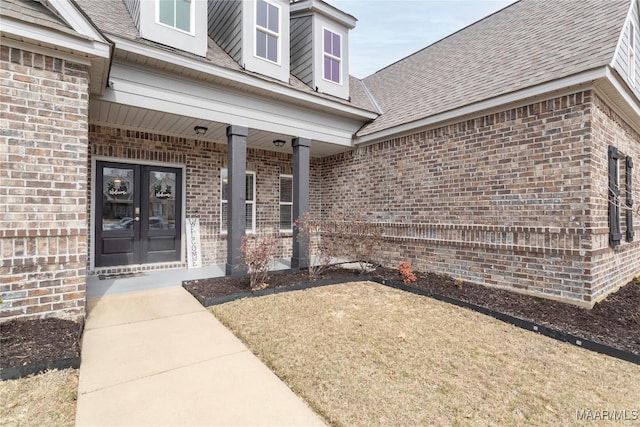 property entrance featuring french doors, brick siding, and a shingled roof