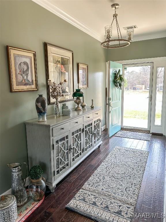 entryway featuring a notable chandelier, visible vents, ornamental molding, and dark wood-style flooring