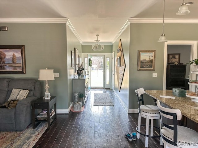 entryway featuring a chandelier, baseboards, dark wood finished floors, and ornamental molding