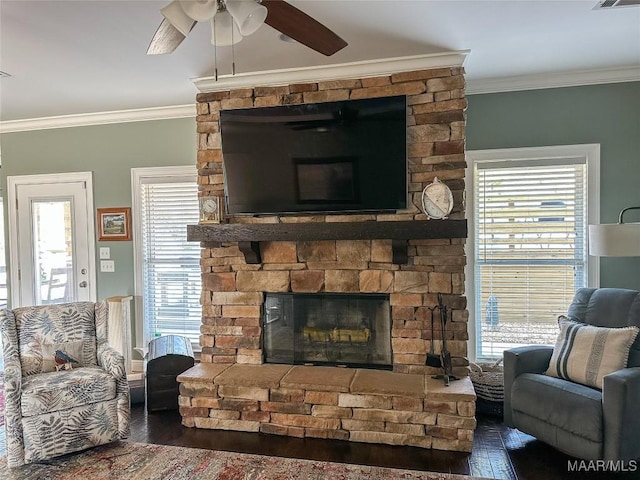 living area with a fireplace, visible vents, ornamental molding, ceiling fan, and wood finished floors