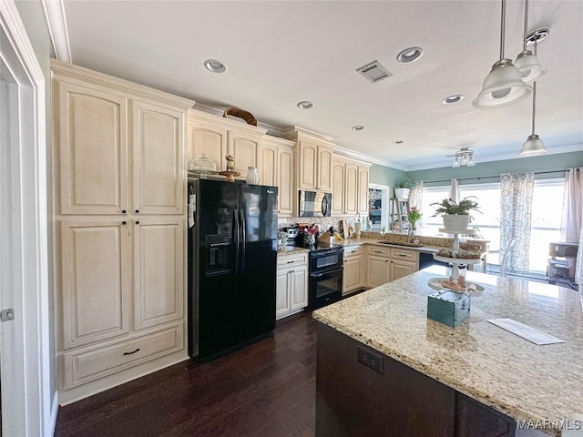 kitchen with visible vents, dark wood finished floors, light stone counters, cream cabinets, and black appliances