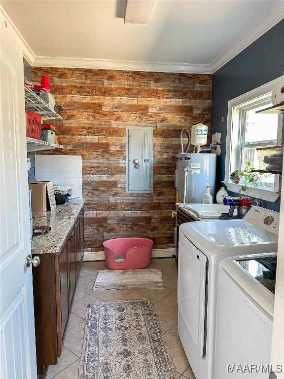 washroom with light tile patterned floors, ornamental molding, washing machine and dryer, electric water heater, and laundry area