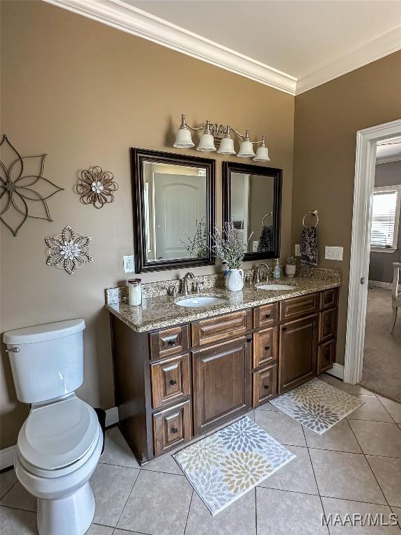 bathroom with crown molding, double vanity, a sink, and tile patterned floors