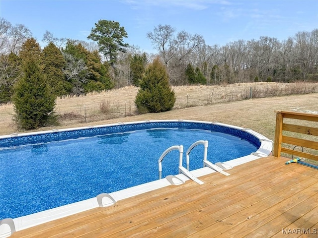 outdoor pool with a wooden deck and fence