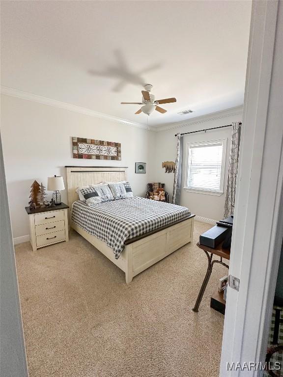 bedroom featuring visible vents, baseboards, light colored carpet, and crown molding