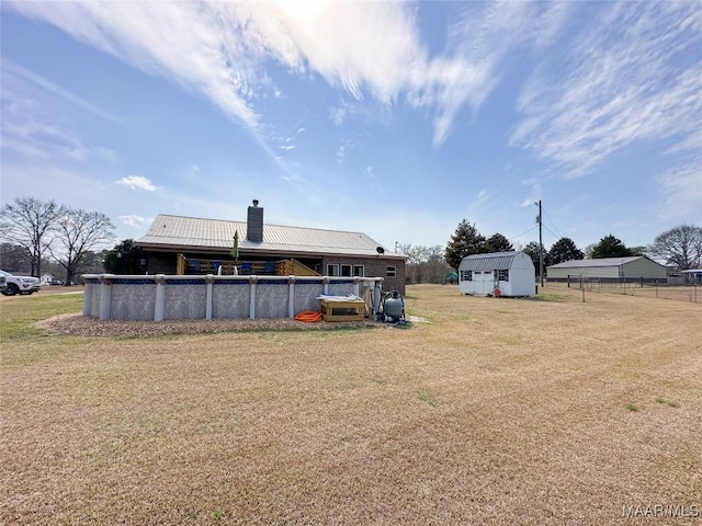 view of yard featuring an outbuilding, an outdoor pool, and fence