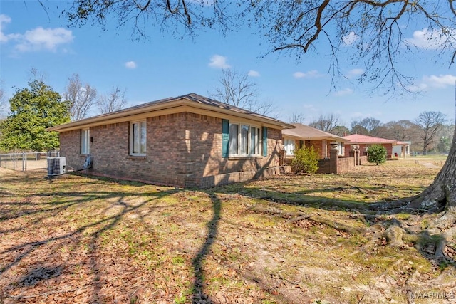 view of home's exterior featuring a yard, central AC unit, fence, and brick siding