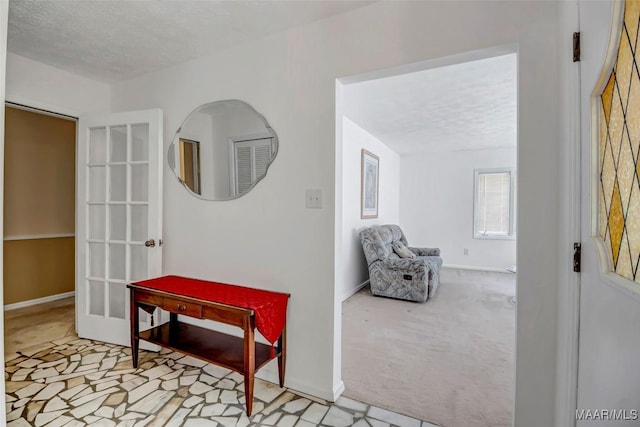 corridor with carpet floors, a textured ceiling, and baseboards