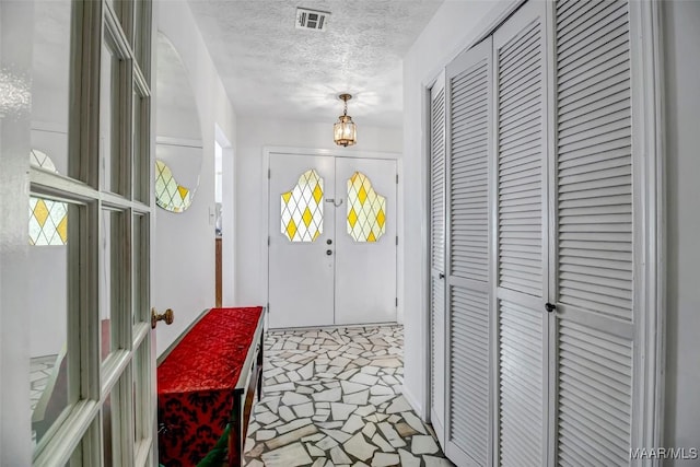 entrance foyer featuring visible vents, a textured ceiling, and french doors