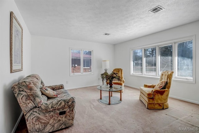 sitting room featuring a textured ceiling, carpet flooring, visible vents, and baseboards