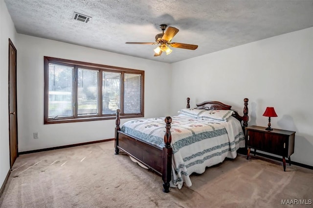 bedroom featuring a textured ceiling, light carpet, a ceiling fan, visible vents, and baseboards