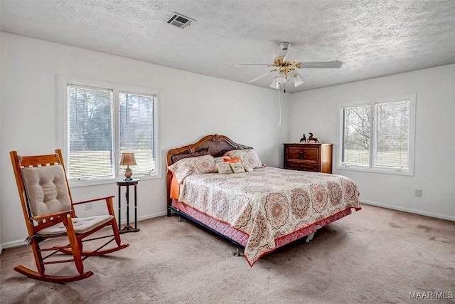 carpeted bedroom featuring a textured ceiling, ceiling fan, visible vents, and baseboards