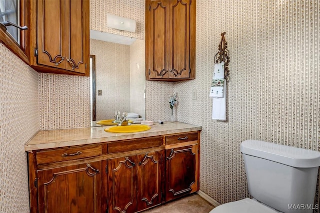 bathroom with vanity, toilet, and wallpapered walls