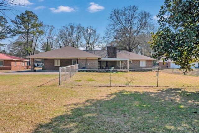 rear view of property with a chimney, fence, a lawn, and brick siding