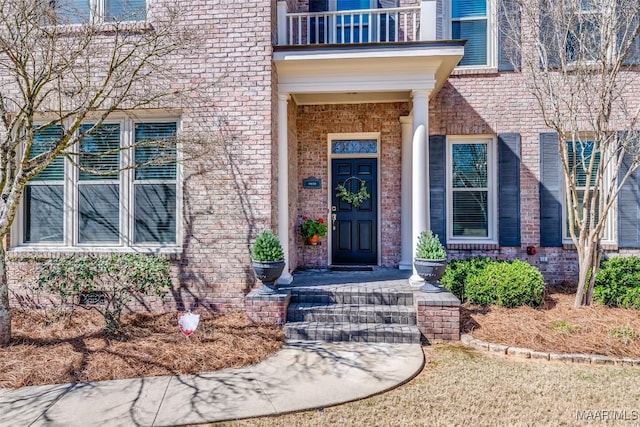 property entrance with a balcony and brick siding