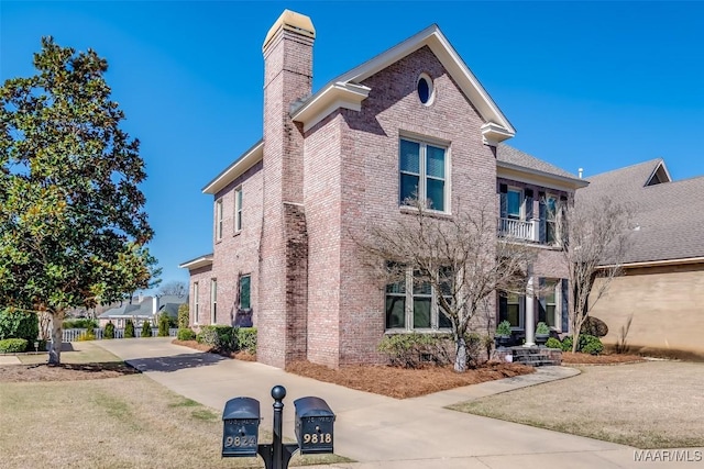 view of front of property with brick siding, a chimney, and a balcony