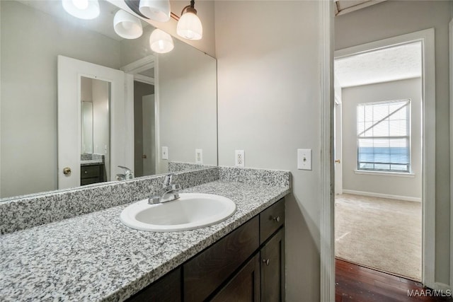 bathroom with baseboards, wood finished floors, and vanity