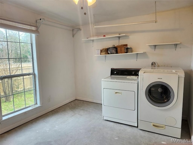 clothes washing area with laundry area, separate washer and dryer, plenty of natural light, and baseboards