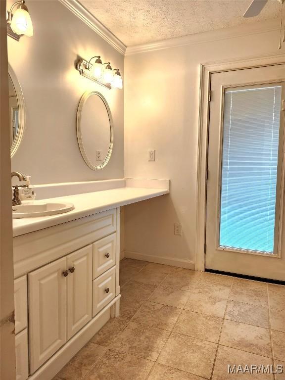 bathroom with baseboards, ornamental molding, a textured ceiling, and vanity