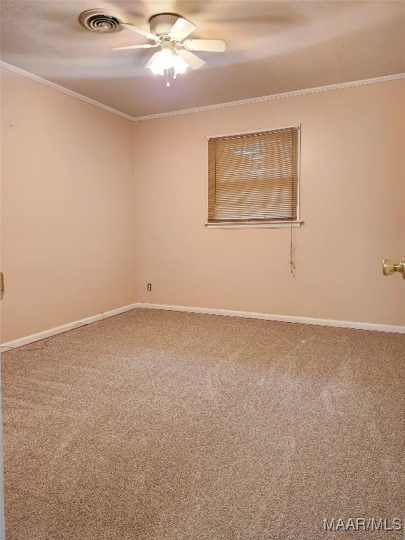 unfurnished room featuring carpet floors, visible vents, baseboards, a ceiling fan, and ornamental molding