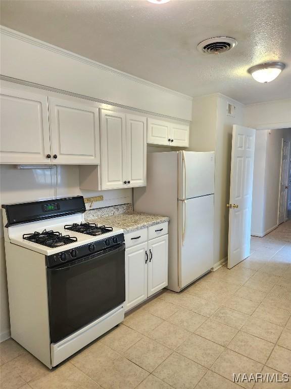 kitchen featuring white appliances, visible vents, a textured ceiling, and white cabinets