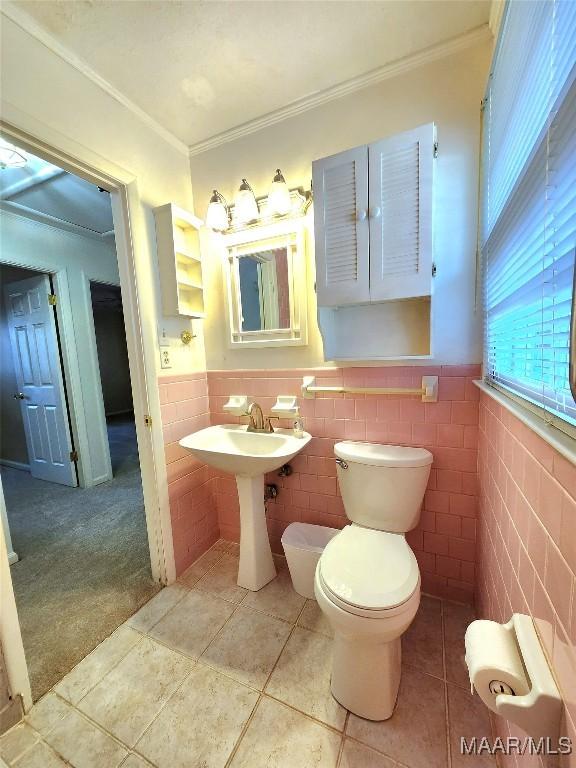 bathroom featuring a wainscoted wall, ornamental molding, tile patterned flooring, and toilet