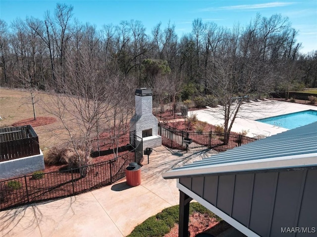 view of patio / terrace featuring fence, a community pool, and an outdoor fireplace