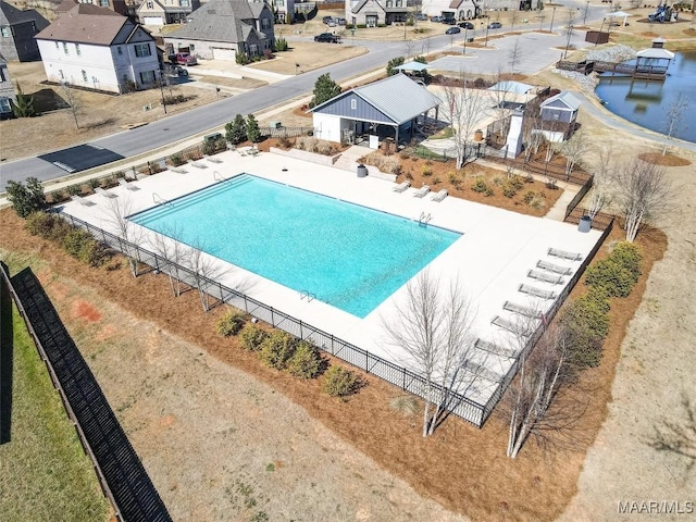 pool featuring a water view, a patio area, a residential view, and fence