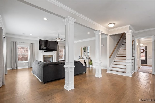 living area featuring a fireplace, decorative columns, and wood finished floors