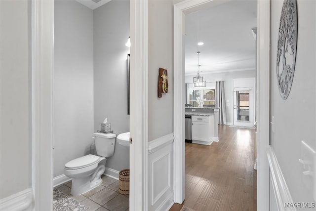 bathroom with toilet, baseboards, wood finished floors, and ornamental molding