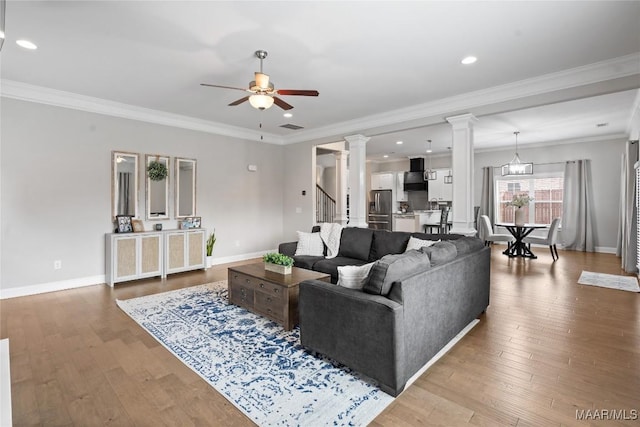 living area featuring ornate columns, baseboards, a ceiling fan, and hardwood / wood-style floors