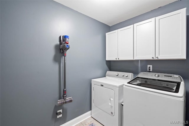 laundry area featuring cabinet space, washing machine and dryer, light tile patterned floors, and baseboards