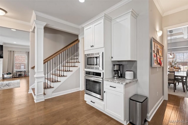 kitchen featuring dark wood-style flooring, crown molding, stainless steel appliances, backsplash, and ornate columns