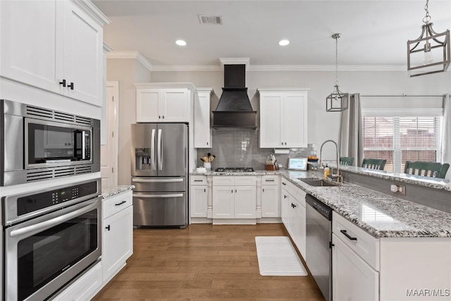 kitchen featuring visible vents, appliances with stainless steel finishes, a peninsula, custom exhaust hood, and a sink