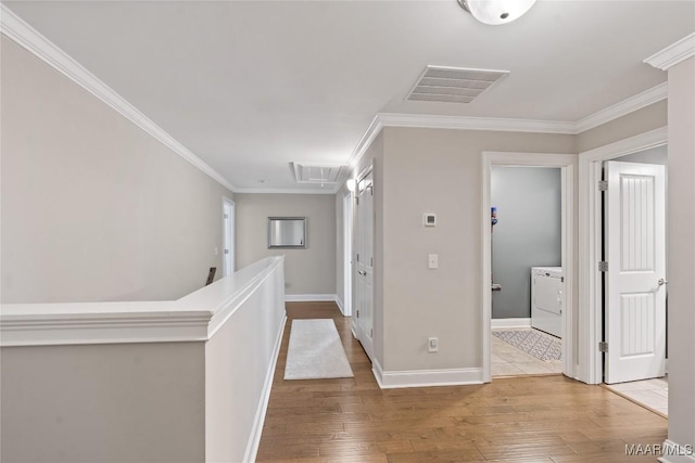 corridor with washer / clothes dryer, visible vents, crown molding, and wood finished floors