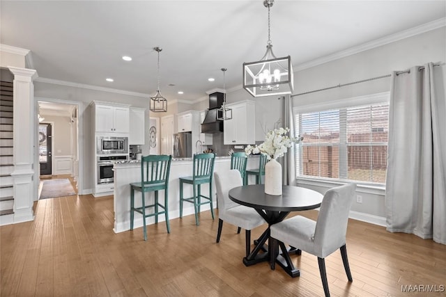 dining area featuring recessed lighting, ornate columns, crown molding, and light wood finished floors