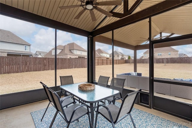 sunroom / solarium with a wealth of natural light, a residential view, ceiling fan, and lofted ceiling with beams