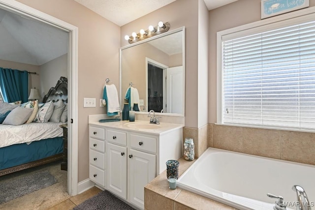 ensuite bathroom with a textured ceiling, connected bathroom, vanity, a bath, and tile patterned floors